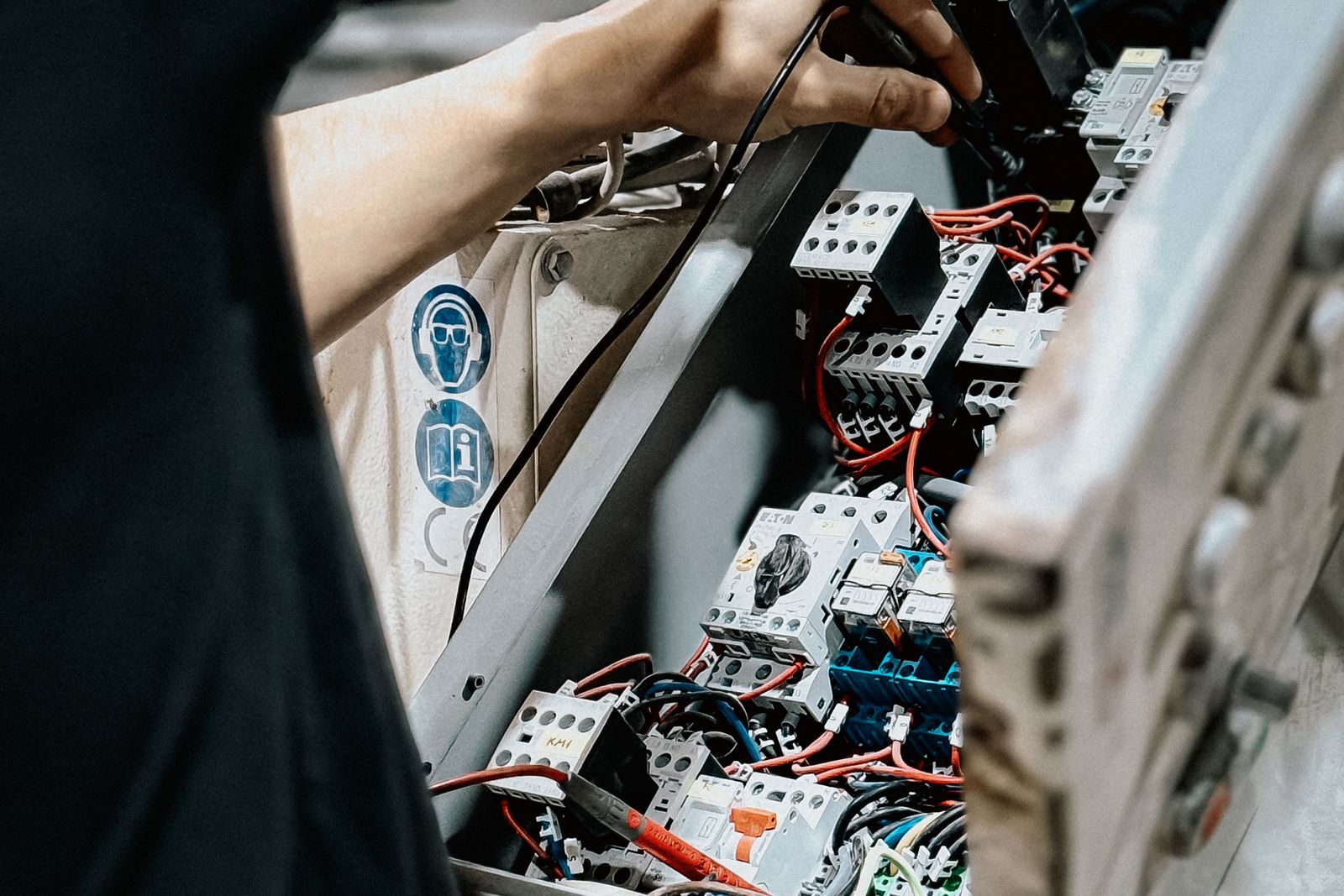 A technician adjusting wiring inside an electrical control panel during maintenance.