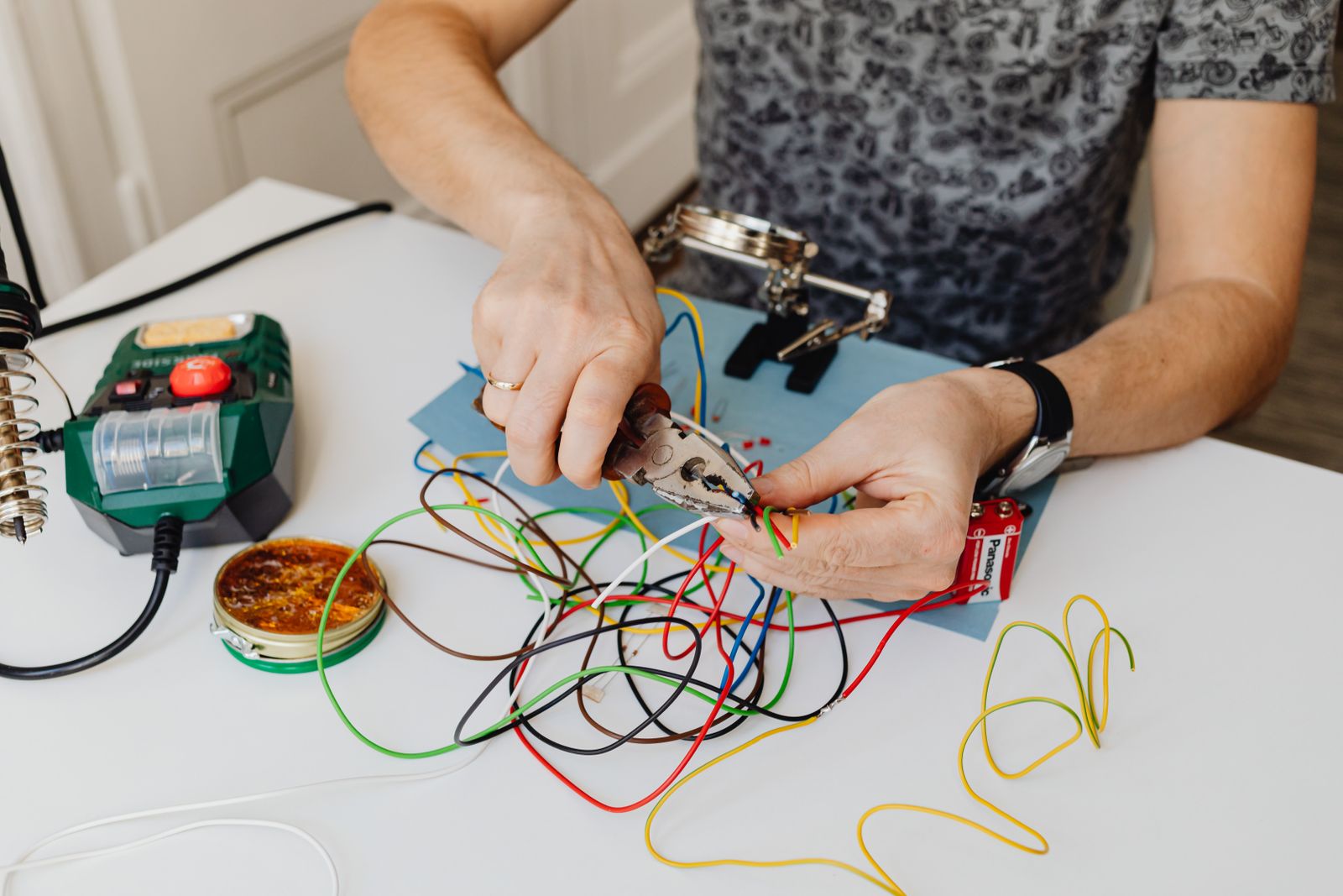 Close-up of gloved hands sorting coloured branch-circuit conductors before making connections.